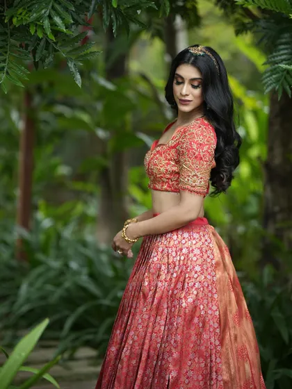 A side profile showcasing the detailed embroidery on the blouse sleeve and the rich texture of the brocade lehenga.