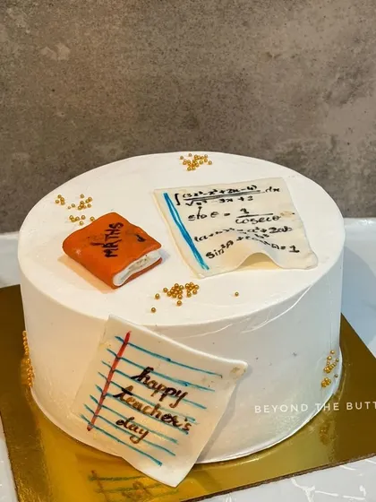 A Teacher's Day cake decorated with edible, handwritten math equations and a tiny fondant book.