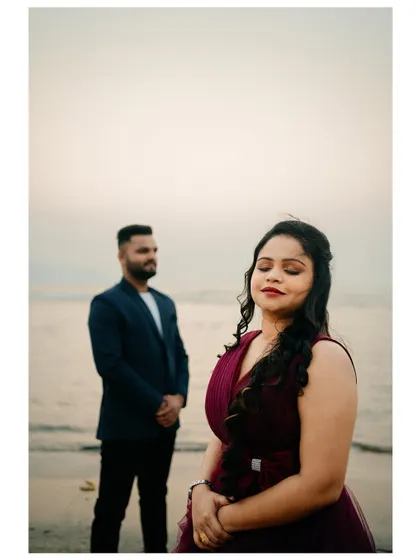 A serene portrait of the bride-to-be on the beach, with her partner in the background. This style of shot tells a story.