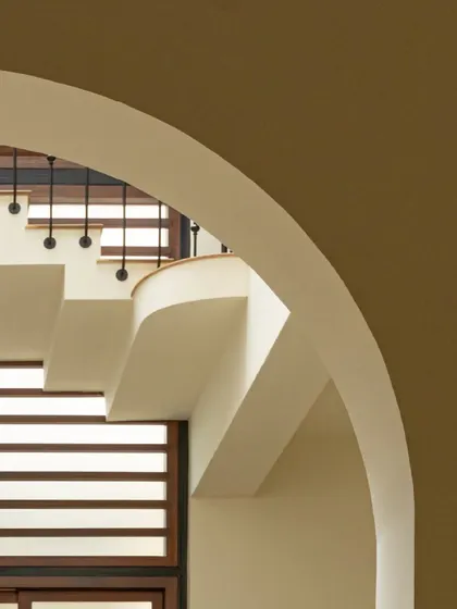 Looking up at the floating staircase through a soft arch. This view captures the interplay of curves, lines, and light that defines the architectural character of the home.