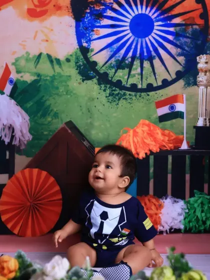 Looking up with wonder, this baby enjoys the festive atmosphere of our Independence Day studio setup, complete with tricolor pom-poms and decorations.