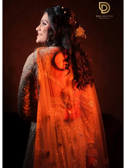 A beautiful back-profile shot of the bride, highlighted with warm, golden light. This portrait showcases the intricate details of her hairstyle and the elegant back of her gown.