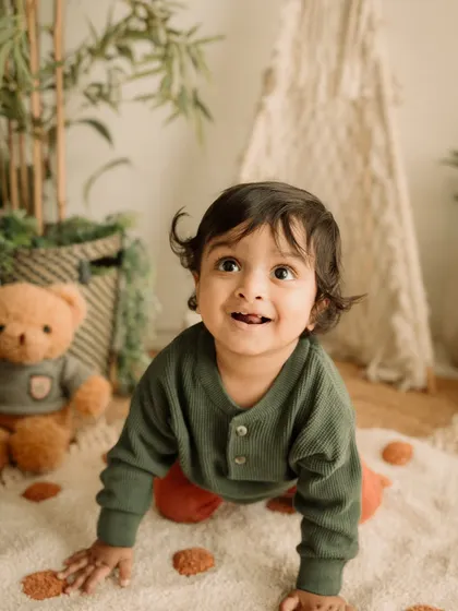 The curious gaze of a toddler exploring the studio, with his teddy bear companion nearby.