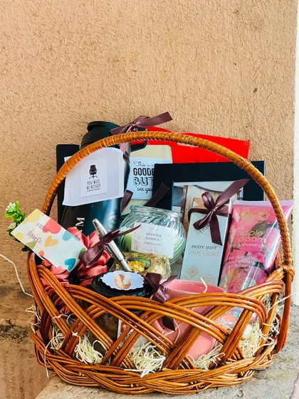A full view of the farewell gift basket, packed with a water bottle, photo frame, snacks, and personal care items.