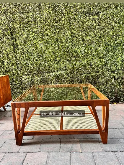 A straight-on view of the coffee table against a green hedge.