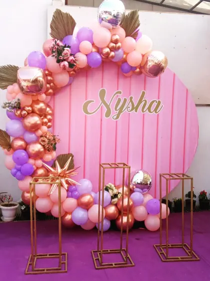 A lovely pink, purple, and rose gold circular backdrop for a birthday party, ready for a cake table.