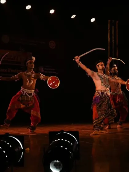 A frontal view of a Chhau trio advancing with swords and shields. This angle highlights the intricate costumes and the focused intensity of the dancers as they move through the choreography.