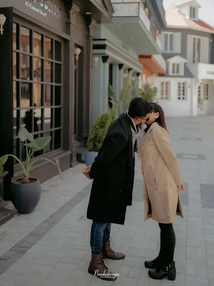 An intimate kiss shared between a couple on a stylish, European-inspired street.