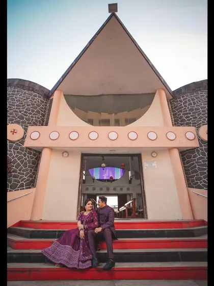 A grand, wide-angle shot of the couple sitting on the steps of the church after their wedding. This photo captures the impressive architecture of the church and the couple's happy moment.