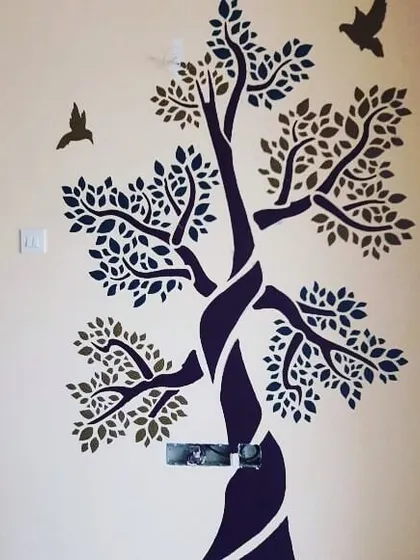 A two-tone tree stencil adds a touch of nature-inspired art to this room. This technique allows for subtle yet impactful wall decor that complements the existing interior design without overwhelming the space.