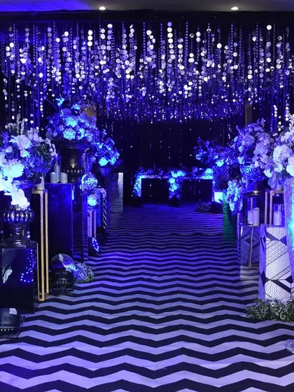A dazzling entrance tunnel for a 'starry night' themed event. The path is lit with dramatic blue light and framed by curtains of hanging silver sequins, creating an immersive and glamorous experience.