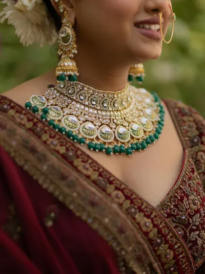 A detailed close-up of the bride's stunning kundan and emerald necklace, highlighting the intricate craftsmanship of her wedding jewelry.