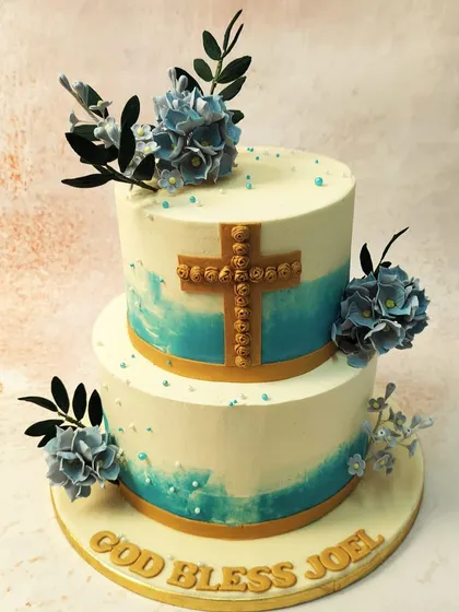 We offer a blessing with this beautiful two-tiered Holy Communion cake. A detailed gold cross is the focal point, complemented by delicate blue flowers and an abstract watercolor effect, creating a design that is both spiritual and artistic.