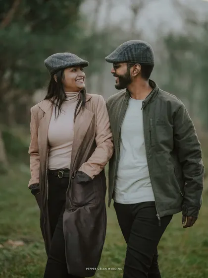 Ananthu and Sarga sharing a smile as they walk together. Their matching hats and coordinated outfits add a charming touch to their vintage-themed shoot.