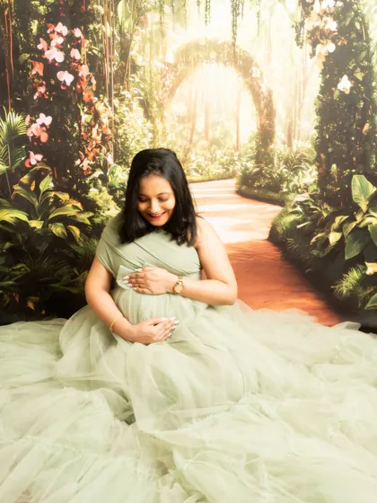 A gentle moment of connection with the baby. This seated portrait against a garden backdrop is serene and full of emotion.