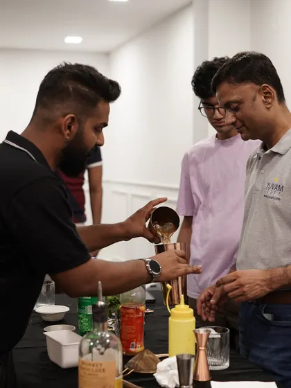 You get to be the bartender, and we're right there with you. Here, I'm guiding a participant through the steps of building a cocktail, ensuring everyone gets personal attention. Our beginner-friendly bartender class is perfect for anyone looking to learn a new skill.