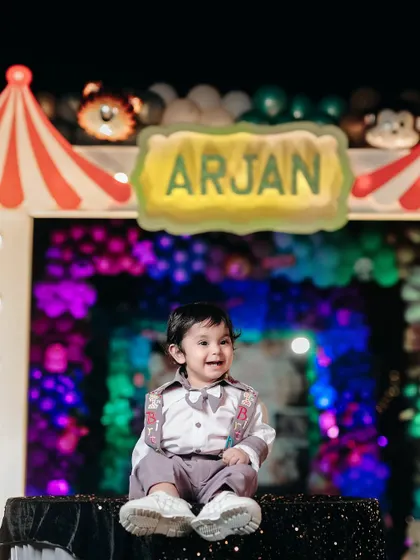 The star of the show. A beautiful shot of the birthday boy sitting in front of his personalized sign at his fun-filled carnival party.