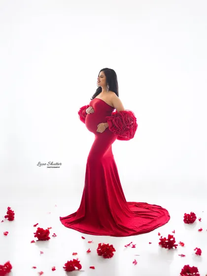 A full-length view of the red gown, surrounded by scattered rose petals for a romantic and beautiful touch.