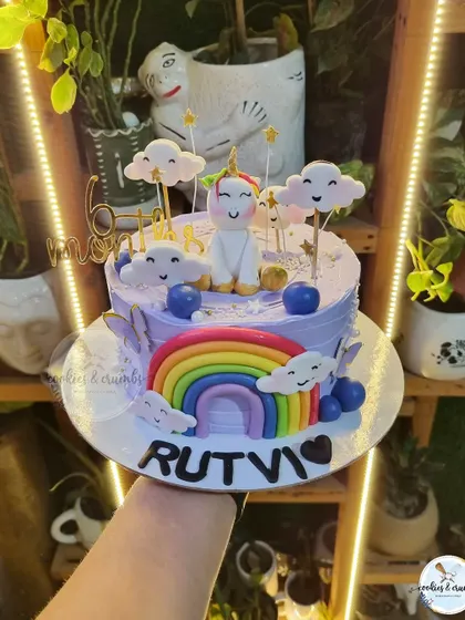 A cute unicorn and rainbow cake for a 6-month birthday. The lavender color, smiling clouds, and fondant unicorn make this a magical way to celebrate a half-birthday milestone.