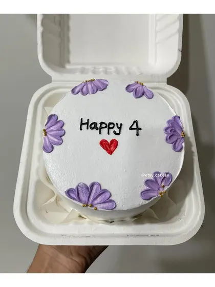 A cute anniversary bento cake with purple flowers celebrating "Happy 4".