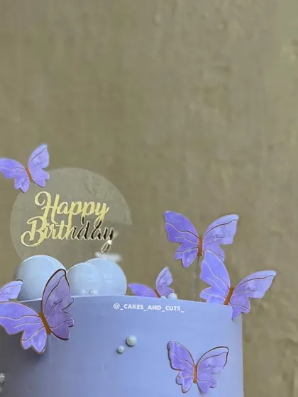 A close-up of the purple butterfly cake, highlighting the translucent "Happy Birthday" topper and the delicate butterflies.