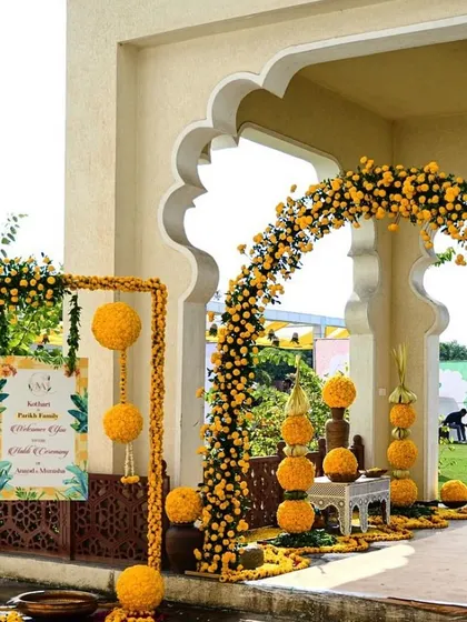 A traditional and auspicious entrance for a Haldi ceremony, featuring an arch made of yellow marigolds and decorative props.