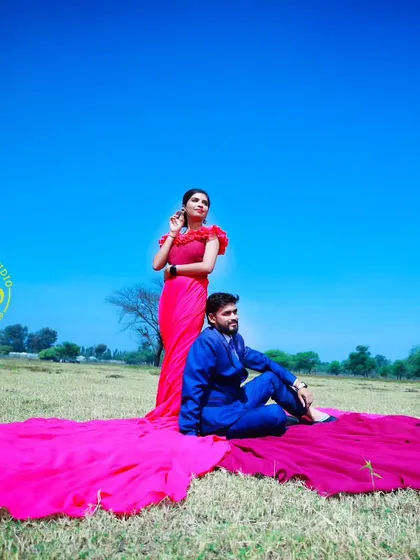 A bold and vibrant outdoor photoshoot. The contrast between her pink flying gown and his royal blue suit, both provided by me, creates a visually stunning image.