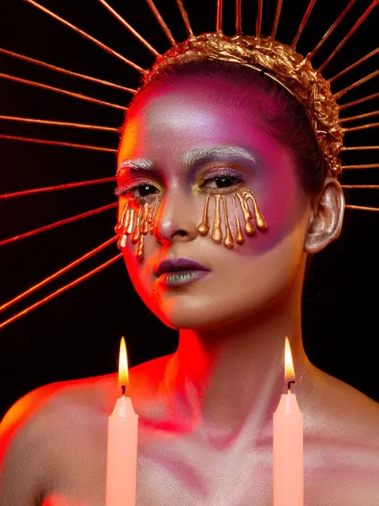 A conceptual portrait titled 'Burning Candles'. This look uses dripping gold makeup effects and creative lighting to create a surreal and artistic image, a style we love to explore in our studio.