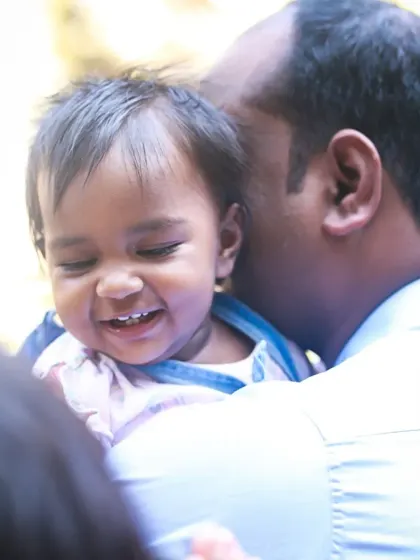 The pure joy on this baby's face is infectious, captured in a candid moment of laughter during a family photoshoot.