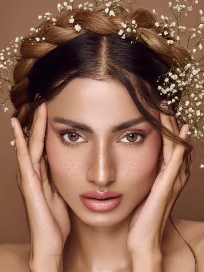 An ethereal, summer-inspired portrait. The model's hair is braided with baby's breath, and her makeup is soft and rosy. The overall feeling is one of whimsical, natural beauty.