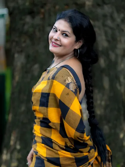A classic portrait in the yellow and black saree, highlighting the traditional braid and simple jewelry. This is a timeless ethnic look.