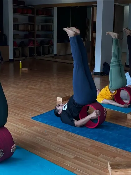 Students in a supported shoulder stand using the yoga wheel. This inversion is great for circulation and relaxation.