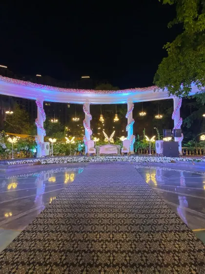 This elegant reception stage, set by a poolside, features a grand white structure with hanging chandeliers and glowing butterfly motifs. We designed it to be a magical focal point for the couple's special evening.