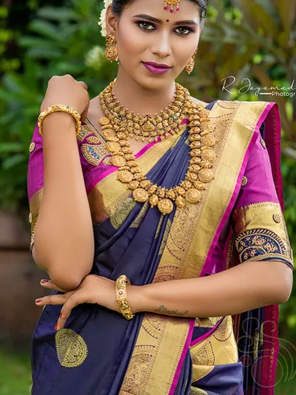 A close-up of the traditional gold jewelry paired with the rich silk saree.