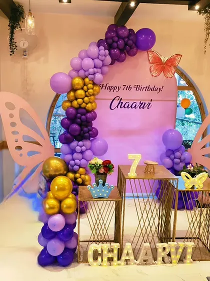 Chaarvi's 7th birthday was a sophisticated butterfly theme with a rich purple and gold color scheme. The decor features elegant butterfly wings, a custom backdrop, and metallic balloon accents for a touch of glamour.