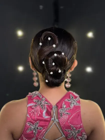 A variation of the pearl-adorned sleek bun, this time with a different swirl pattern, showing how the style can be customized.