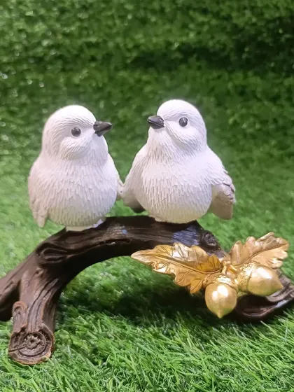 A close-up of the bird couple, showing the detailed texture of the feathers and the delicate golden leaves.