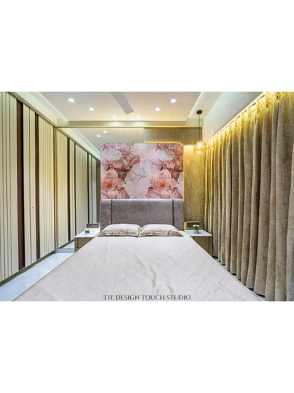 A full view of the bedroom, showing the interplay between the floral headboard, the neutral-toned wardrobes, and the warm, ambient lighting. The space feels both luxurious and inviting.