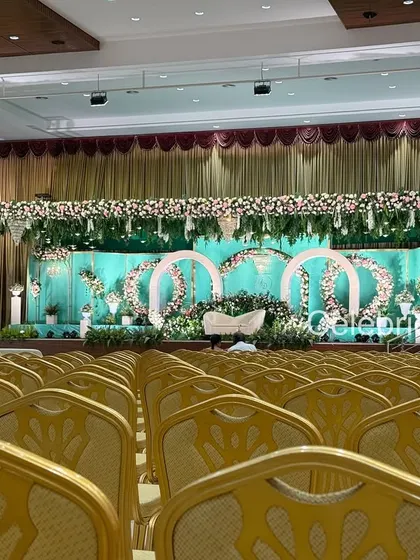 A full view of a convention hall transformed for a wedding reception. The seating arrangement, stage decor, and lighting are all meticulously planned to create a cohesive and elegant look.