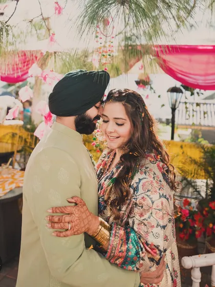 A sweet embrace. The soft green of the groom's outfit beautifully complements the earthy tones in the bride's printed kaftan.