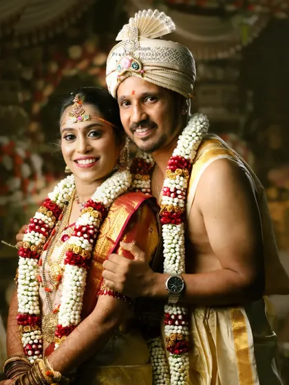 A portrait of the bride and groom in traditional wedding attire, showcasing the beautiful garlands and their happy smiles. This is a timeless shot from their wedding ceremony.