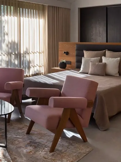 We introduced soft pink armchairs into this bedroom at the Mango Orchard House to create a comfortable seating nook. The chairs add a gentle touch of color that complements the earthy tones of the room.