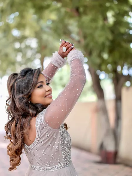 Reception ready in a stunning silver gown. The makeup is soft yet glamorous, with shimmering eyes and beautiful curls, creating a look that is perfect for celebrating the night away.