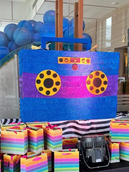 A piñata designed to look like a retro boombox cassette player, surrounded by colorful gift bags. This was a perfect fit for a Rockstar-themed party.