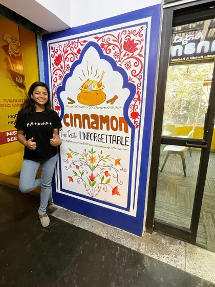 Here I am with a completed Jharokha-style mural for Cinnamon, a restaurant in Bangalore. This design incorporates their logo and branding into a traditional Indian architectural frame.