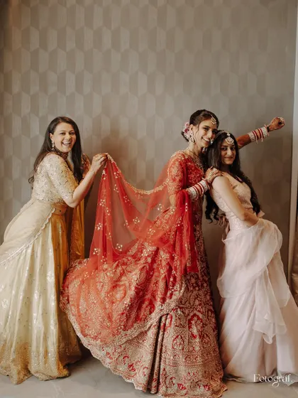 Bridesmaids assemble! A fun, playful shot of the bride with her friends, who are helping with her veil and striking superhero poses.