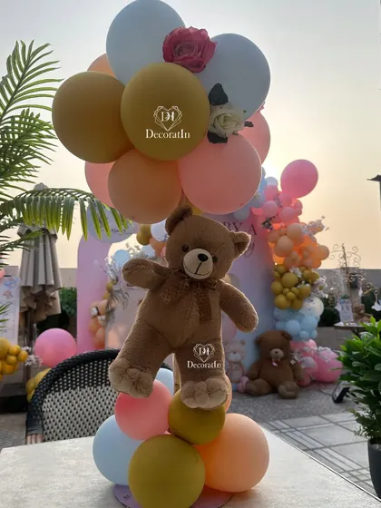 A cute teddy bear and balloon centerpiece for a guest table.