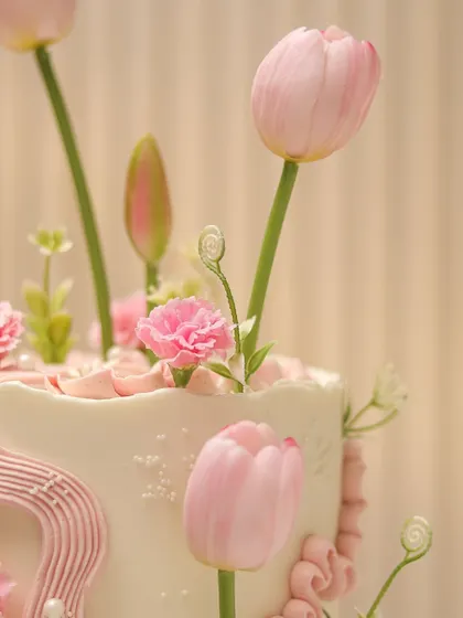 A close-up of the incredibly realistic sugar tulips and carnations on this cake. Our sugar flower classes teach you how to craft each petal for a lifelike appearance.