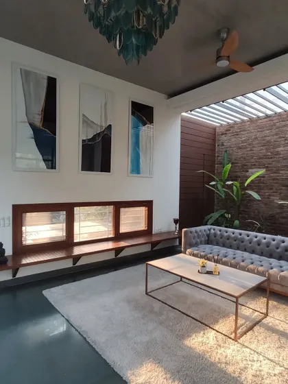 The skylit lounge area, where a comfortable sofa sits between an indoor garden and a wall of custom art, creating a perfect space for relaxation.