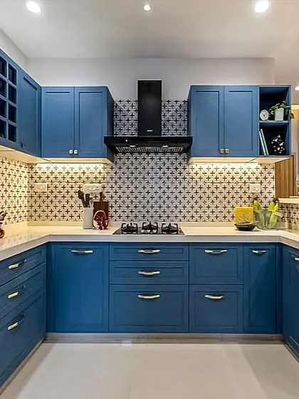 A beautiful U-shaped kitchen in a classic blue shaker style. The design includes open wine storage, under-cabinet lighting, and a patterned backsplash for a touch of elegance.